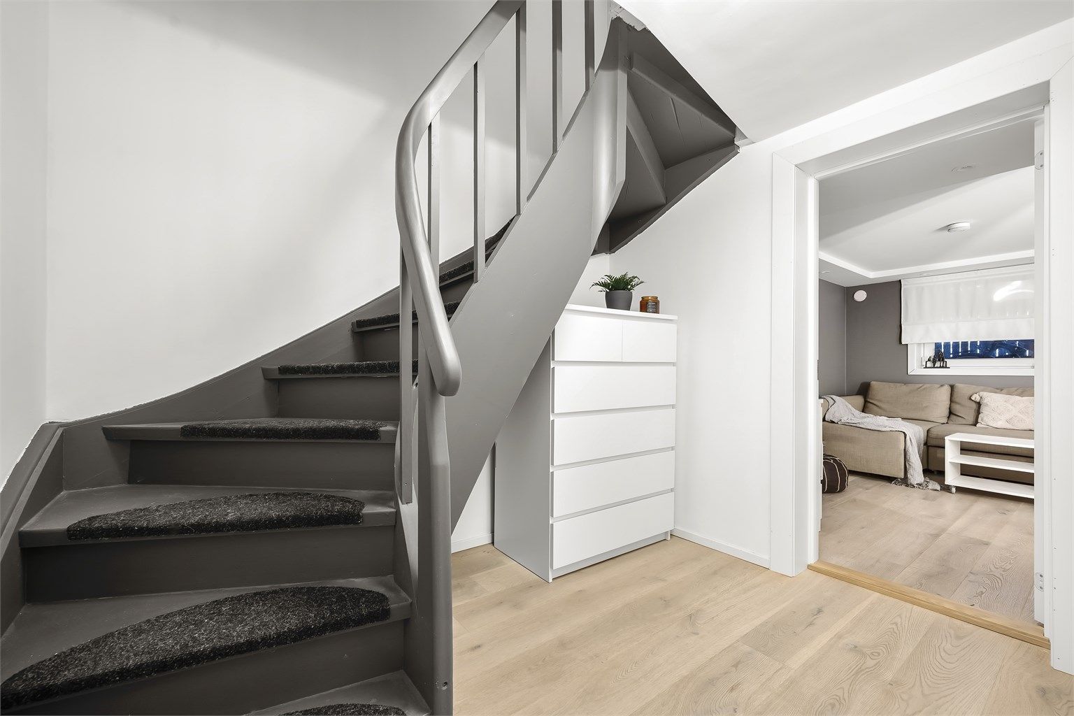 Vi går ned i underetasjen. Her finner du en romslig gang med plass til oppbevaring under trappen, bad 2, kjellerstue og bod.