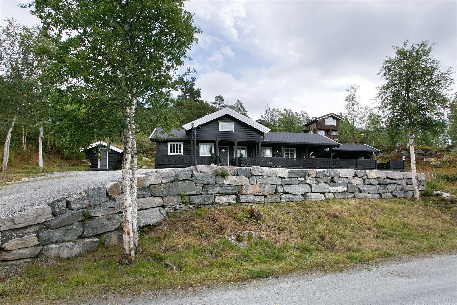 Fasade og pent opparbeidet natursteinsmur på tomten
