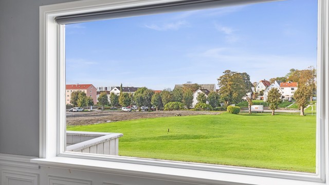Utsikt fra stuevinduet over det åpne grøntarealet like utenfor.