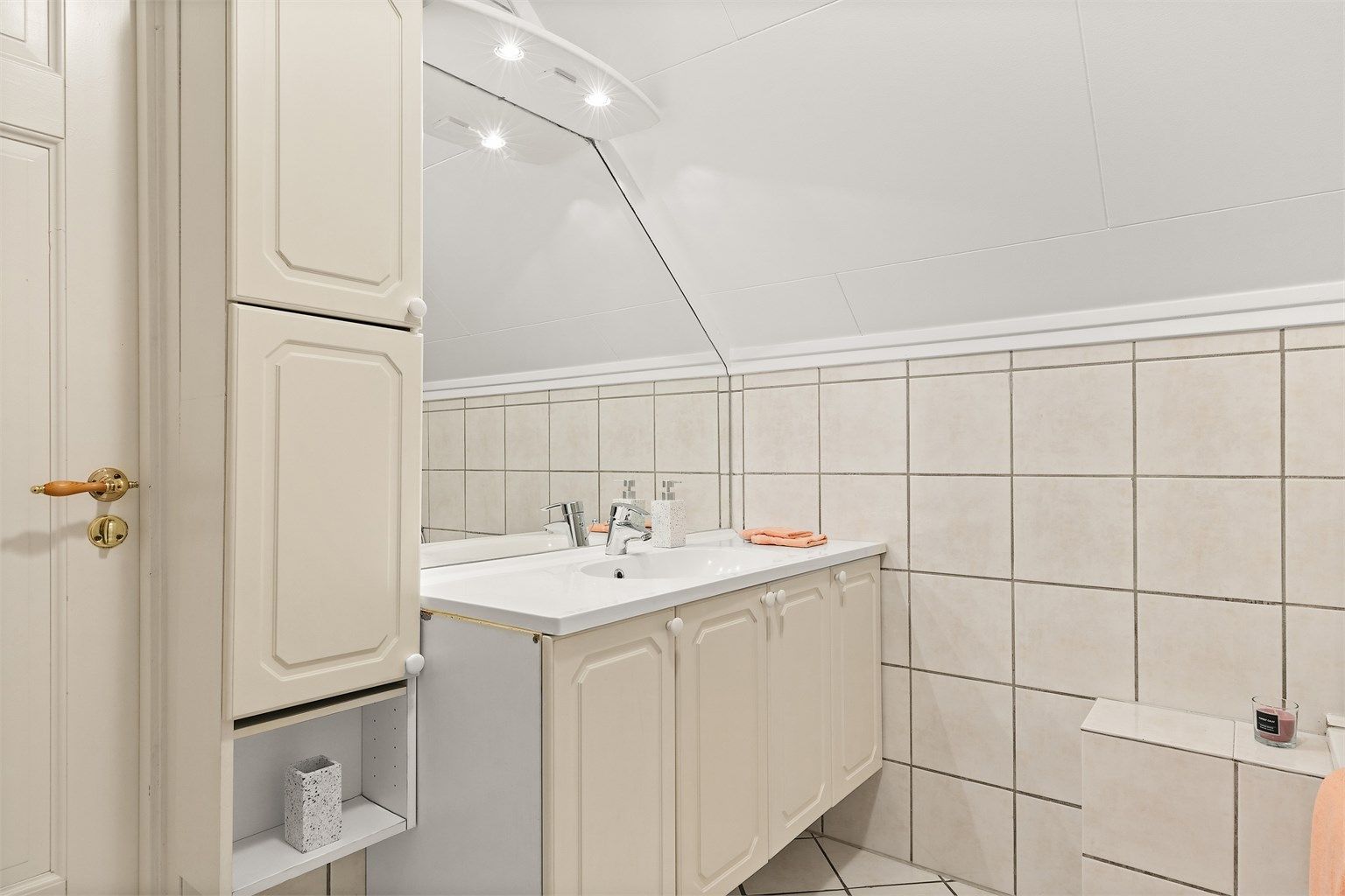 Skap og speil med overlys på vegg over servant.