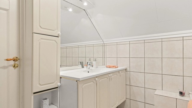 Skap og speil med overlys på vegg over servant.