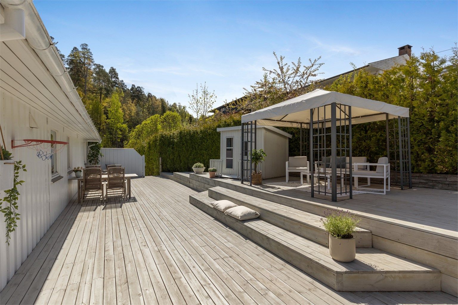 Hovedterrassen er omkranset av hekk mot nabo og har levegg mot gårdsplassen.
