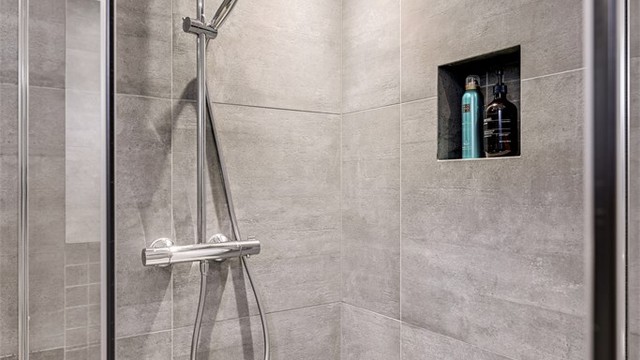 Dusjhjørnet har innfellbare glassdører og en praktisk nisje for oppbevaring.