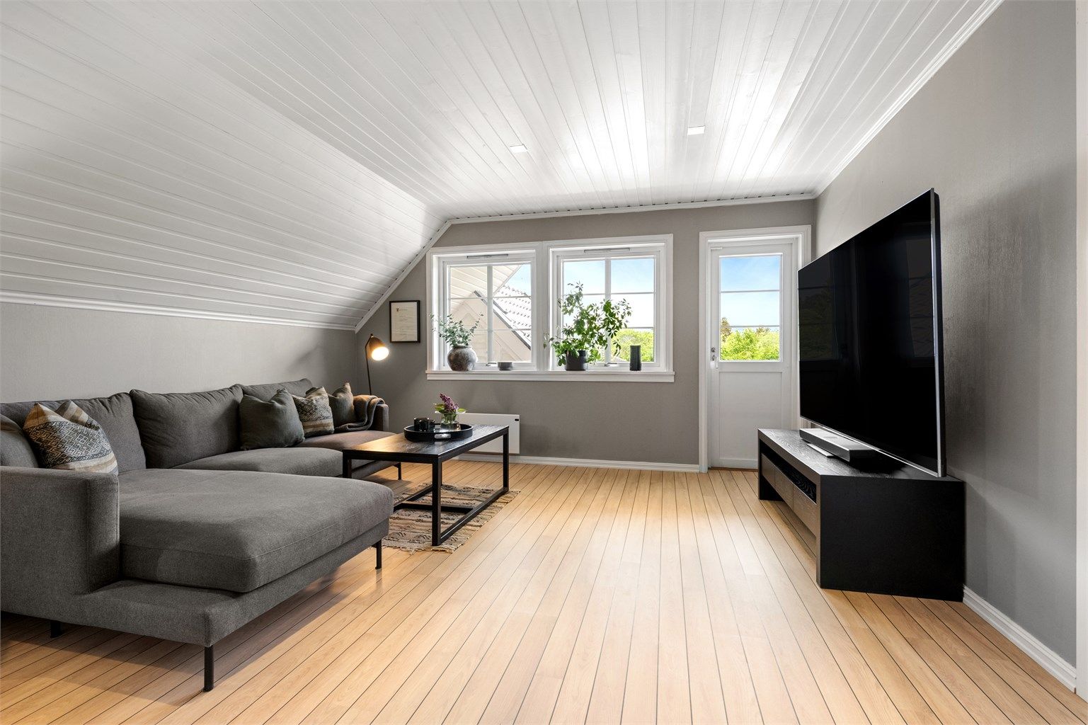Loftstuen er et lyst og luftig rom med god plass til en stor sofagruppe.