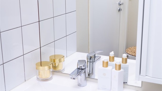 Servantinnredning med speil og overlys samt fliser på vegg.