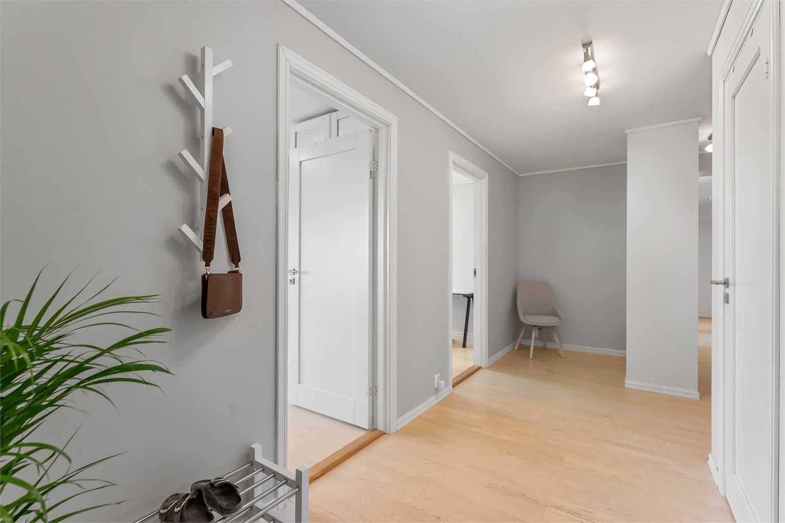 Gang i underetasjen med laminat- og parkettgulv og downlights i himling.