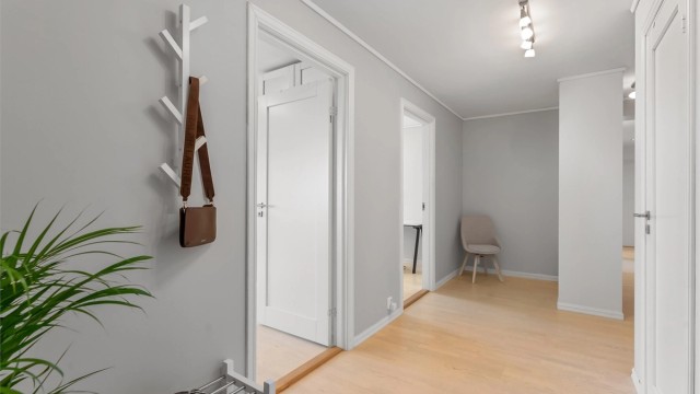 Gang i underetasjen med laminat- og parkettgulv og downlights i himling.