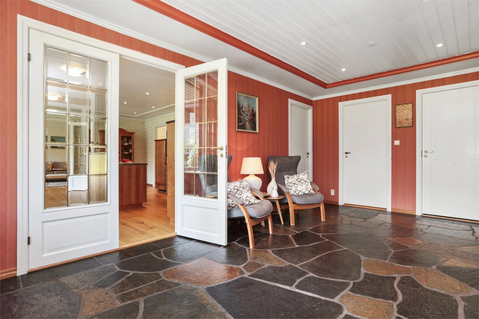 I hallen er det skifer på gulv, tapet på vegger og panelbord i himling. Vannbåren gulvvarme gir behagelig temperatur i huset.