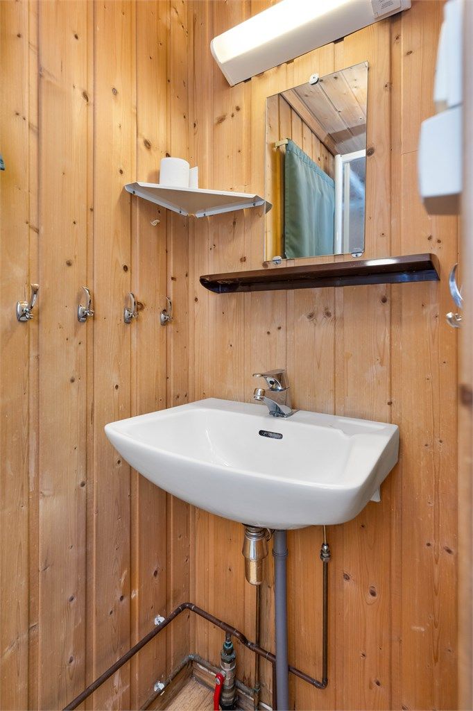 Badet i den tredje enheten, med vegghengt servant og synlige kobberrør.