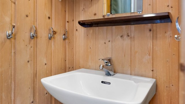 Badet i den tredje enheten, med vegghengt servant og synlige kobberrør.