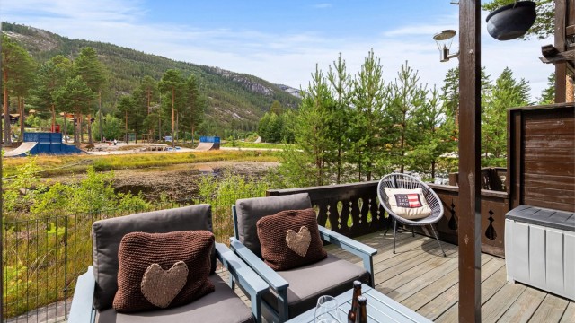 Uteplass med utsikt mot fellesområder og omkringliggende natur.