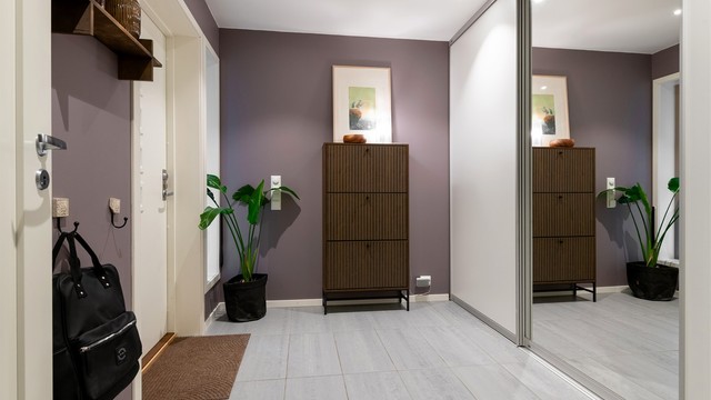 Romslig entré med flislagt gulv, gulvvarme og skyvedørsgarderobe for effektiv oppbevaring.