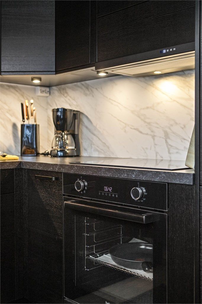 Integrerte hvitevarer, sorte detaljer og lekker splashboard på nytt kjøkken