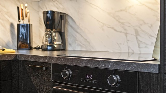 Integrerte hvitevarer, sorte detaljer og lekker splashboard på nytt kjøkken