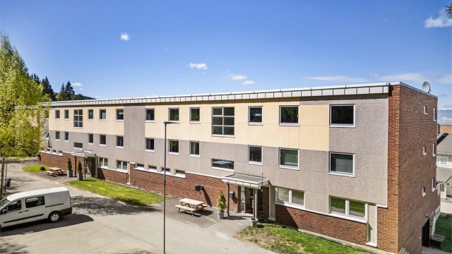 Adkomst via overbygget inngangsparti med callinganlegg og trapp til leilighetens etasjeplan