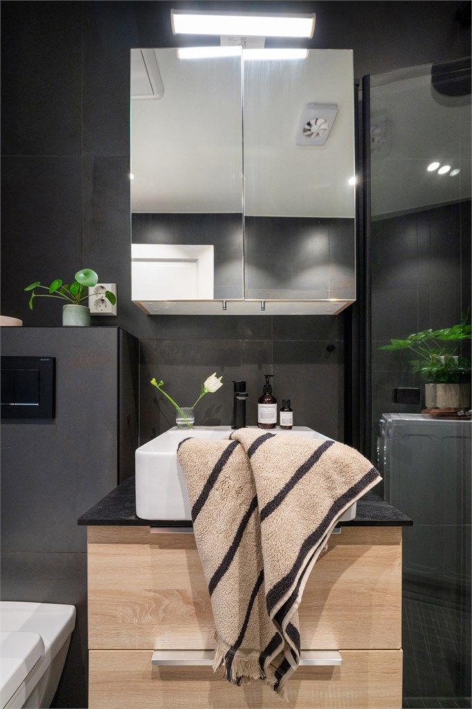 Badet har flislagte overflater, elektrisk gulvvarme og speilskap med integrert belysning.