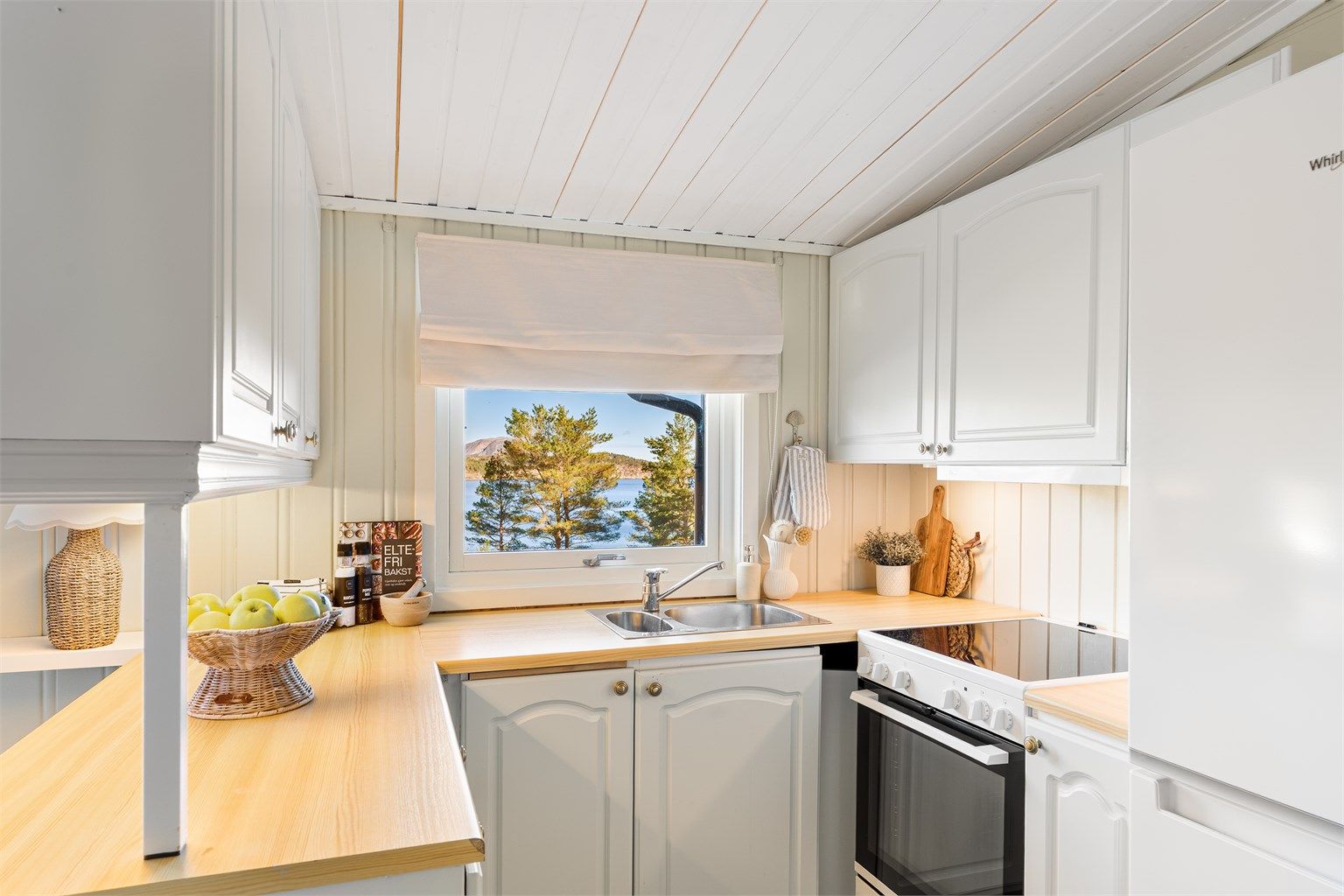 Kjøkkenet ligger naturlig tilbaketrukket fra stuen og er innredet med profilerte fronter og benkeplate av laminat. 