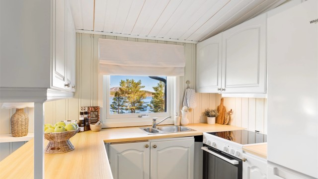 Kjøkkenet ligger naturlig tilbaketrukket fra stuen og er innredet med profilerte fronter og benkeplate av laminat.