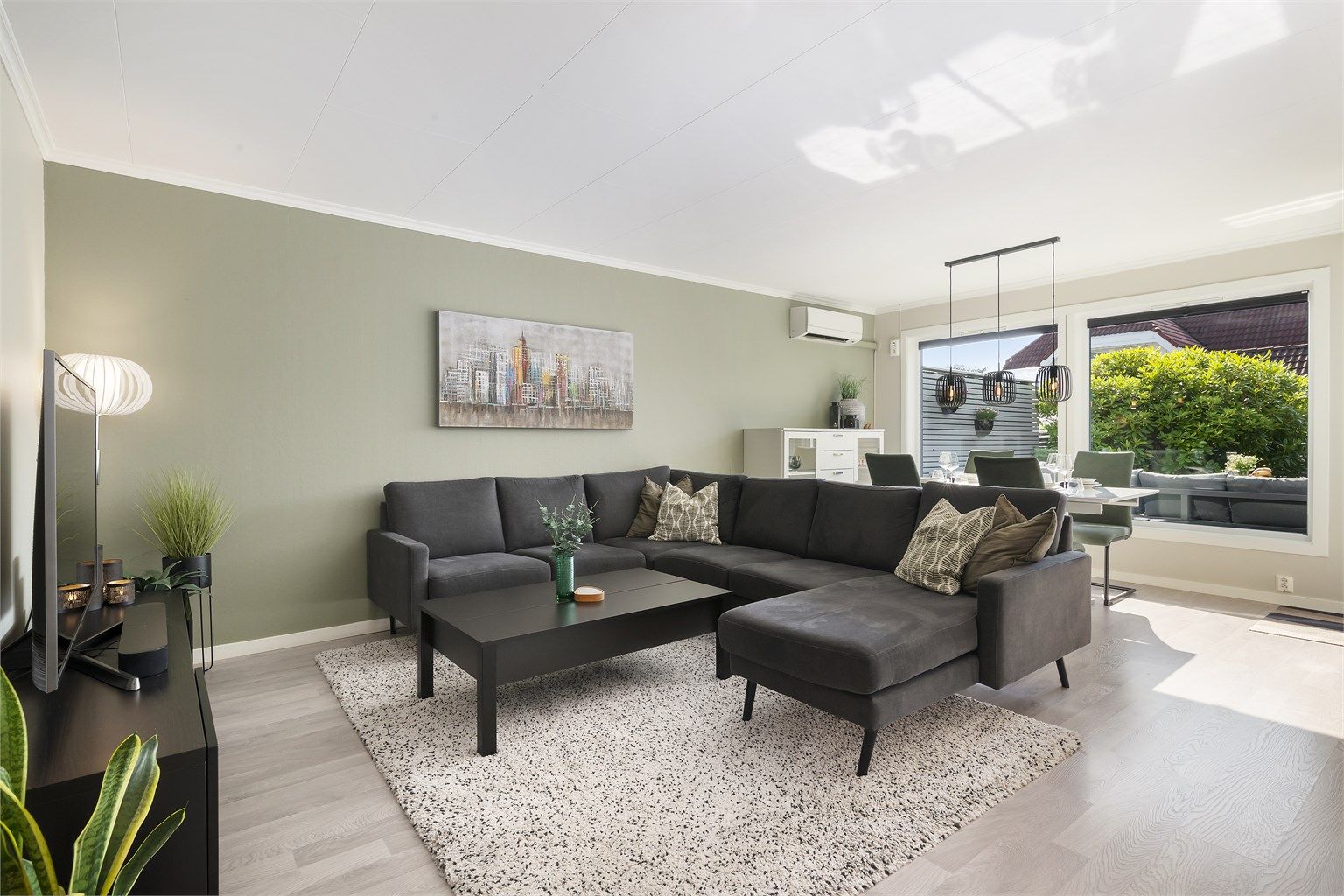 Leiligheten har et åpent og sosialt stue-kjøkkenrom på 32m² med naturlige møbleringssoner. Tvhjørnet er trivelig innredet med sofa og tilhørende bord, samt tv og mediemøblement