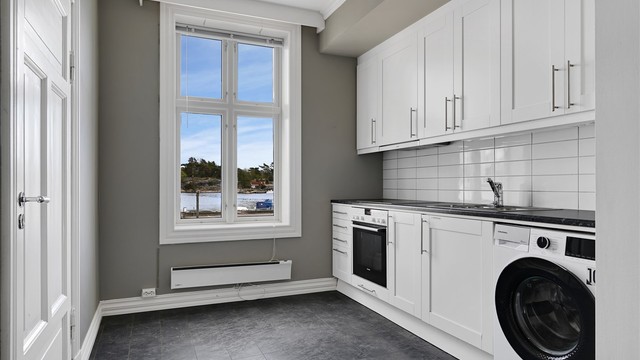 Hyggelig kjøkken med profilerte fronter, integrert stekeovn og platetopp - her er det også opplegg til vaskemaskin