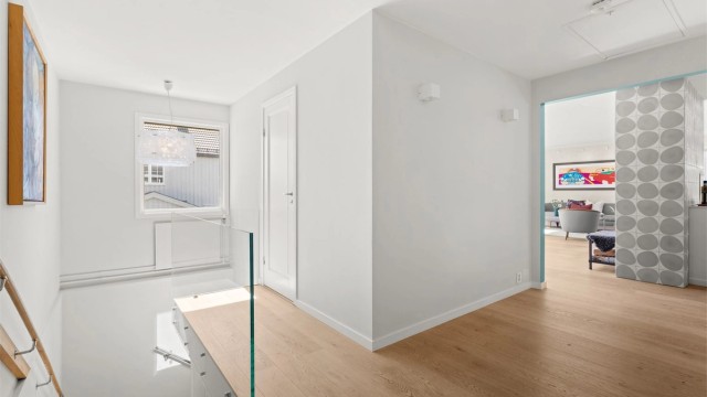 Trappegang med 1-stavs parkett på gulvet og glassrekkverk til trappen. Fra gangen er det adkomst kaldtloft via takluke med stige. Noe lagringsplass på loftet