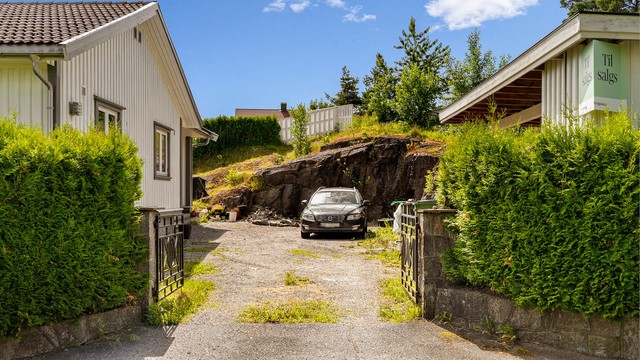 Gruset gårdsplass med parkering for flere biler.