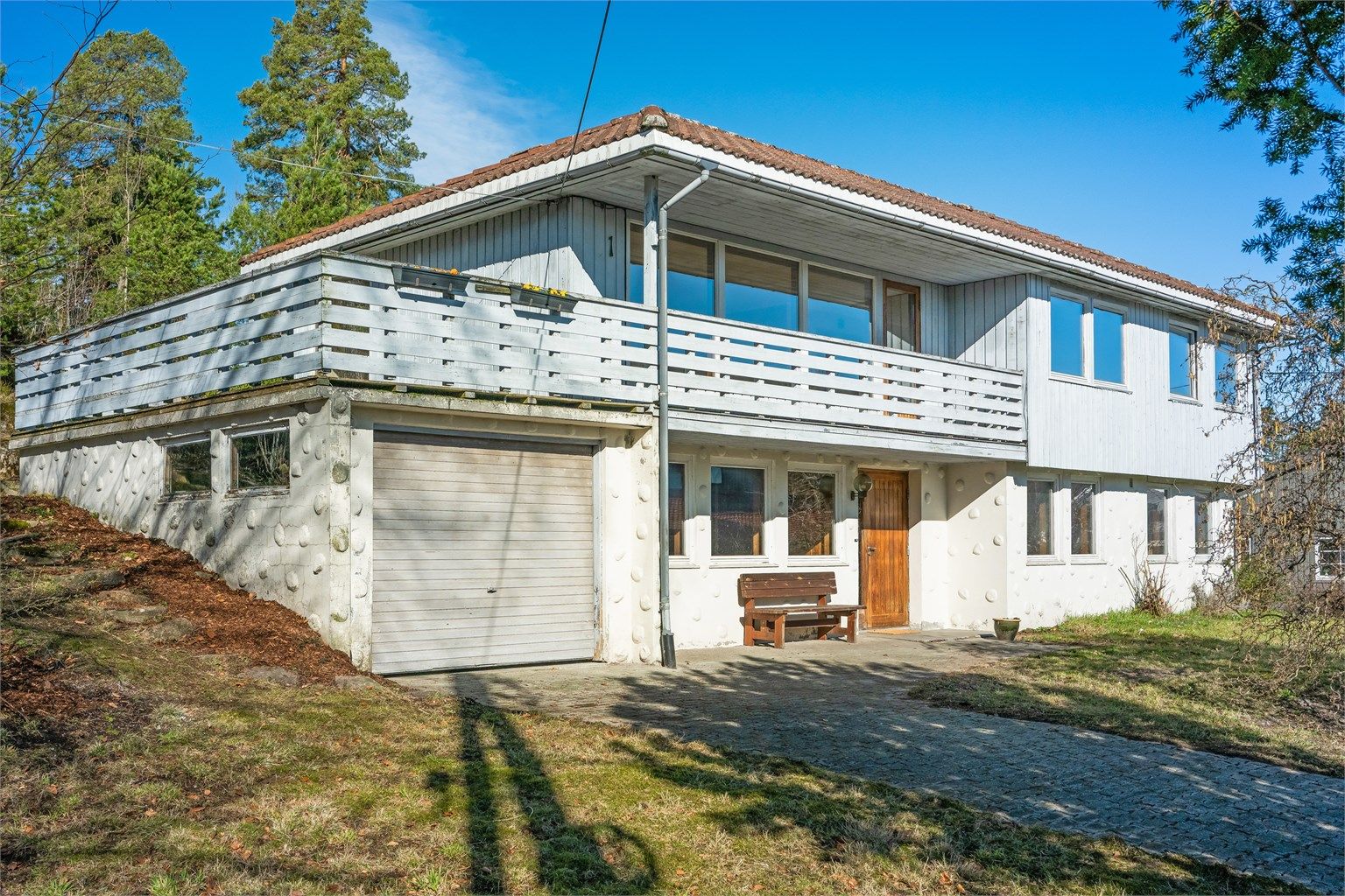 Fasaden har stående bordkledning og grunnmur i lettklinkerblokker, typisk for byggeåret 1974.
