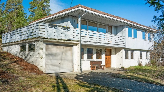 Fasaden har stående bordkledning og grunnmur i lettklinkerblokker, typisk for byggeåret 1974.