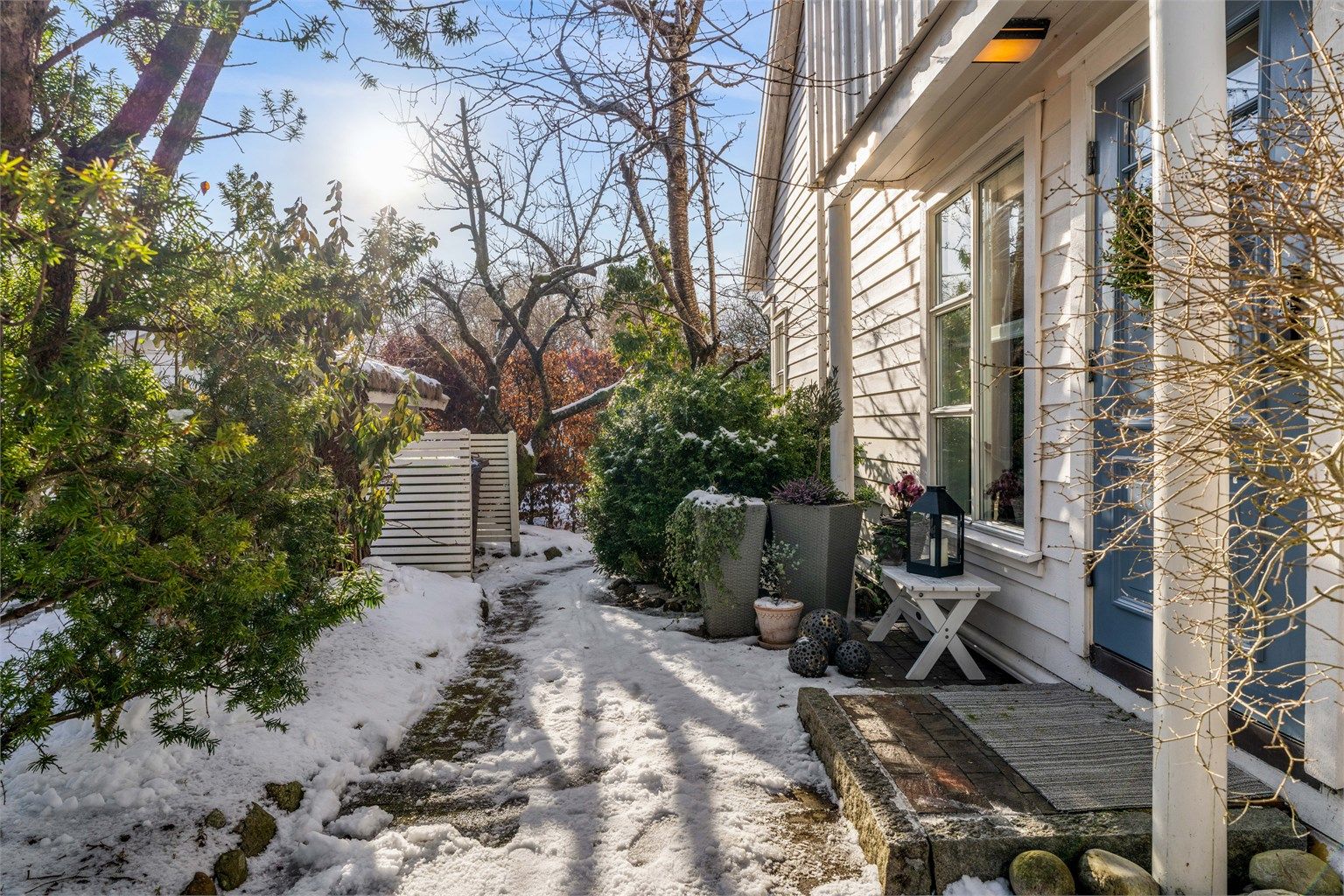 Inngangsparti, med steinbelagt uteareal og passasje inn til hage/uteareal