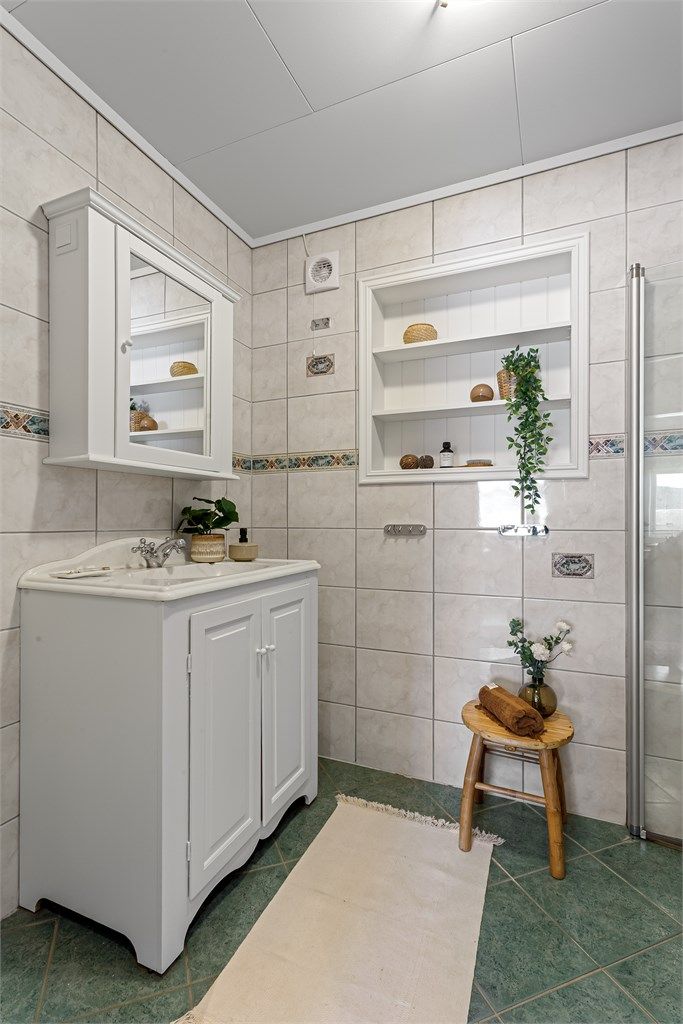 Speilskap på vegg over servant. Plassbygd hylle i vegg. Dusjhjørne med dører og gulvstående toalett.