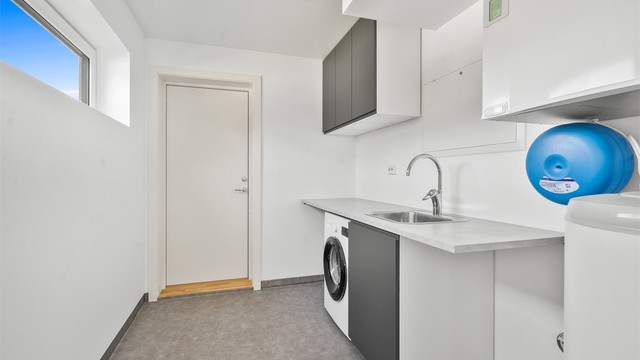 Separat vaskerom/teknisk rom med praktisk benk, skapplass og direkte utgang til carport.