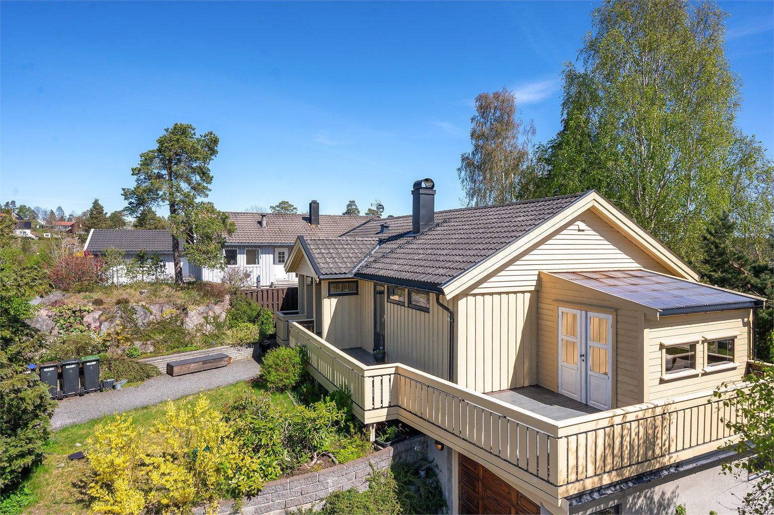 Tomten er svakt skrånende og opparbeidet med  steinheller, plenarealer, støttemurer og  beplantninger.