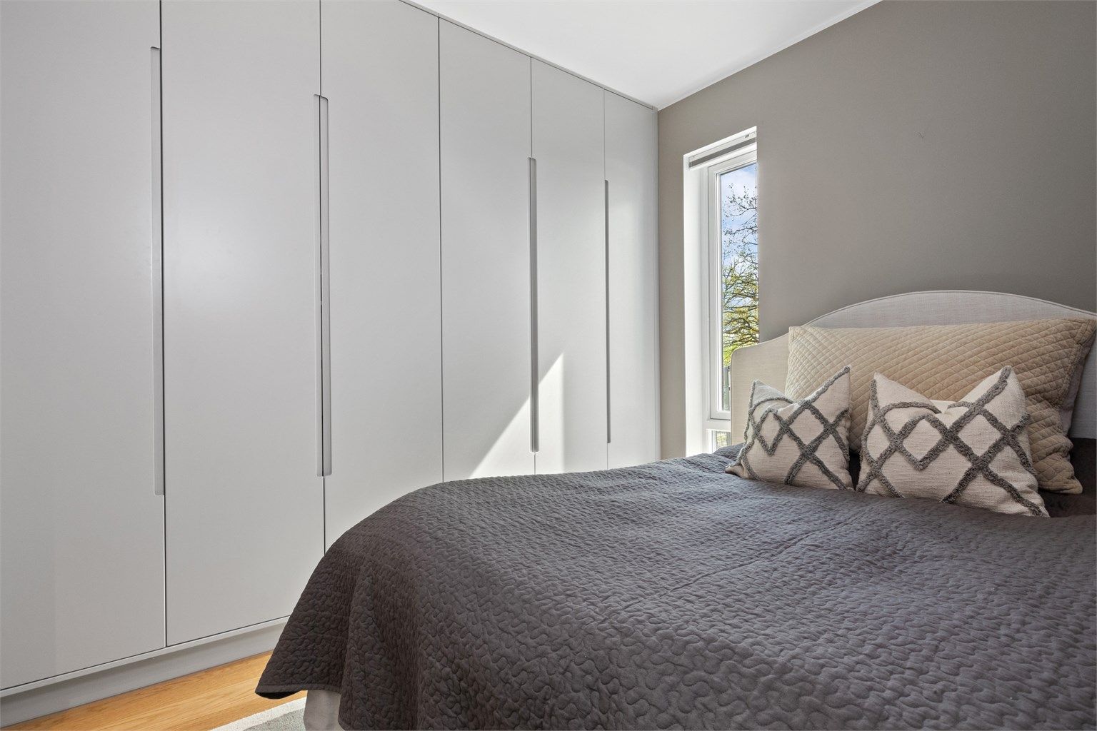 Ett av soverommene har en bred rekke med garderobeskap med innredning i heltre.