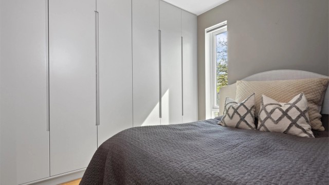 Ett av soverommene har en bred rekke med garderobeskap med innredning i heltre.