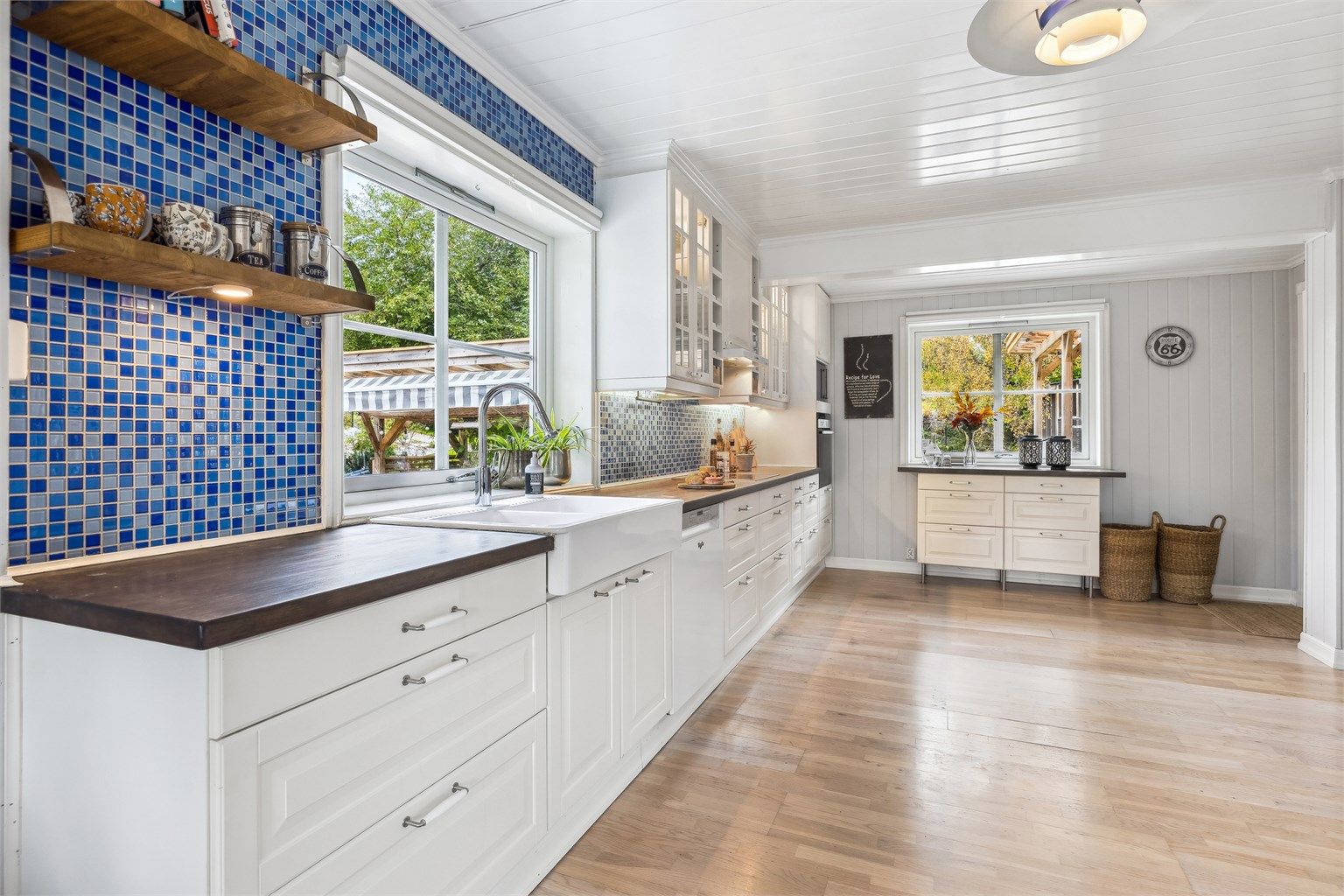 Kjøkkenet er praktisk utstyrt med oppvaskkum i keramikk, enkelte glassfronter og belysning i overskap samt mosaikkfliser på vegg over benken