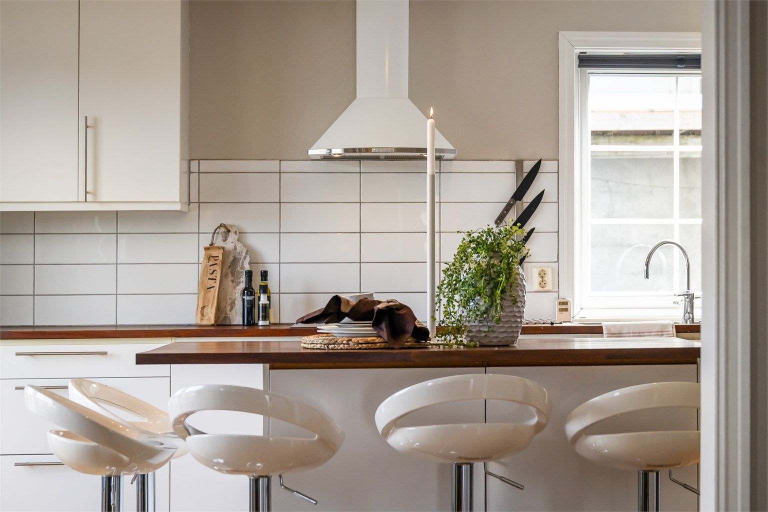 Kjøkkenøy med heltre benkeplate og plass til uformelle måltider. Det er fliser mellom benkeplate og overskap.