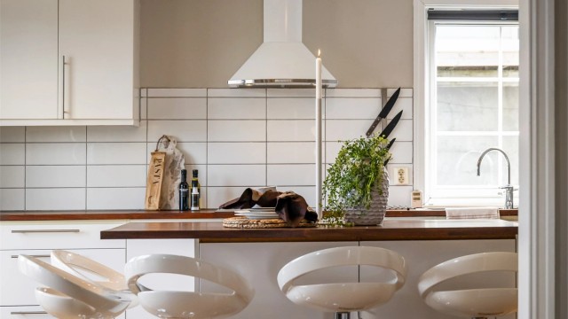 Kjøkkenøy med heltre benkeplate og plass til uformelle måltider. Det er fliser mellom benkeplate og overskap.