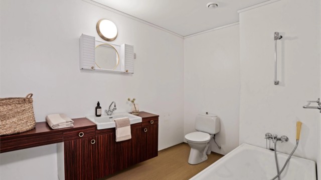 Badet er utstyrt med badekar og en romslig benkeløsning med servant.