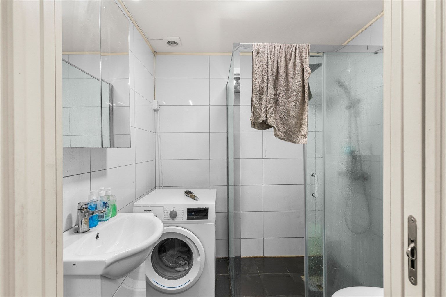Flislagt bad på 3,5 kvm innredet med servantskap med speil, toalett, dusjhjørne og opplegg for vaskemaskin. Badet er opprinnelig byggemeldt som en del av garasjen. Det er ikke søkt bruksendring fra tilleggsdel til hoveddel. 