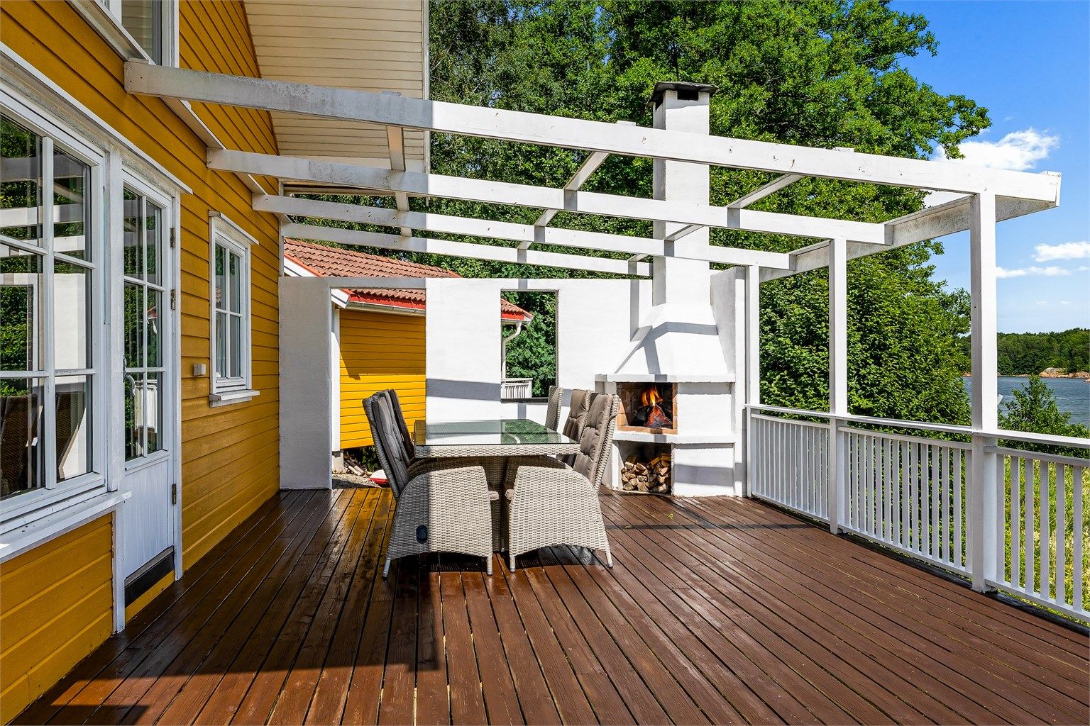 På terrassen vendt mot sjøen er det bygget utepeis og pergola. Her kan du for eksempel trekke over seilduk. Det er rikelig med plass til langbord, og med fyr på peisen ligger alt til rette for lange sommerkvelder.