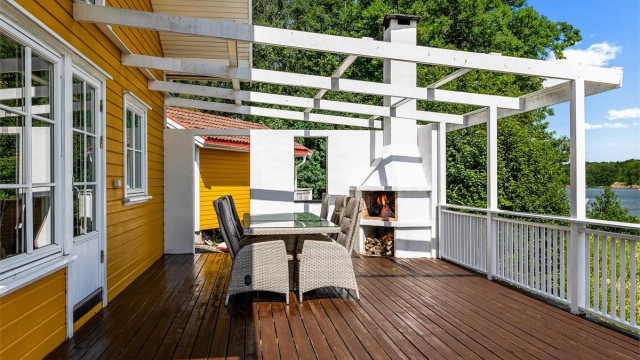 På terrassen vendt mot sjøen er det bygget utepeis og pergola. Her kan du for eksempel trekke over seilduk. Det er rikelig med plass til langbord, og med fyr på peisen ligger alt til rette for lange sommerkvelder.