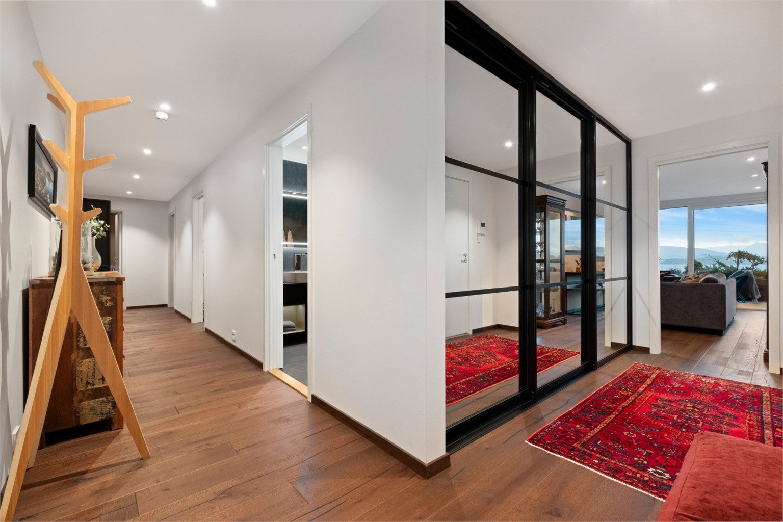 Lys og romslig gang med en-stavs parkett på gulv, malte vegger og tak med innfelt spotter. Stor skyvedørsgarderobe med sort omramming og speilfronter som gir gode oppevaringsmuligheter for yttertøy og sko