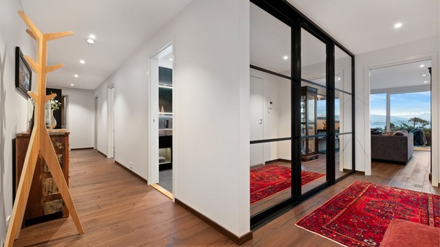 Lys og romslig gang med en-stavs parkett på gulv, malte vegger og tak med innfelt spotter. Stor skyvedørsgarderobe med sort omramming og speilfronter som gir gode oppevaringsmuligheter for yttertøy og sko