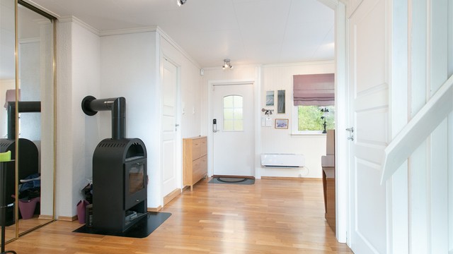 Entré og hall med parkett på gulv, peisovn og luft-til-luft varmepumpe.