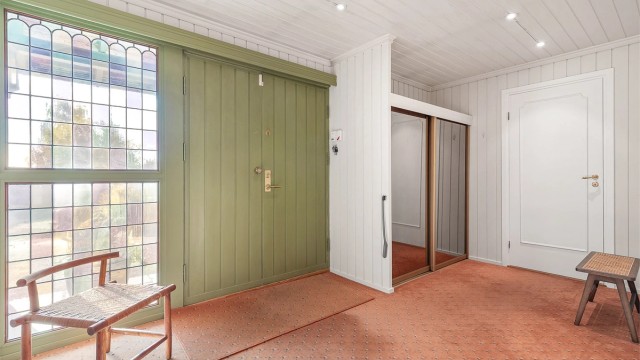 Tidsriktig inngangsdør i en dempet grønnfarge leder inn i en romslig entré