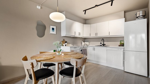 Åpen og sosial kjøkkenløsning med god tilknytning til boligens øvrige oppholdsarealer. Kjøkkeninnredning fra byggeår med tidløse, glatte fronter og laminert benkeplate.