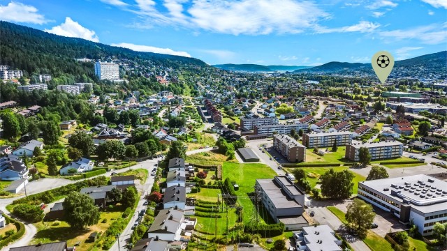 Og Åssiden idrettspark med kunstgressbane og flere gressbaner.