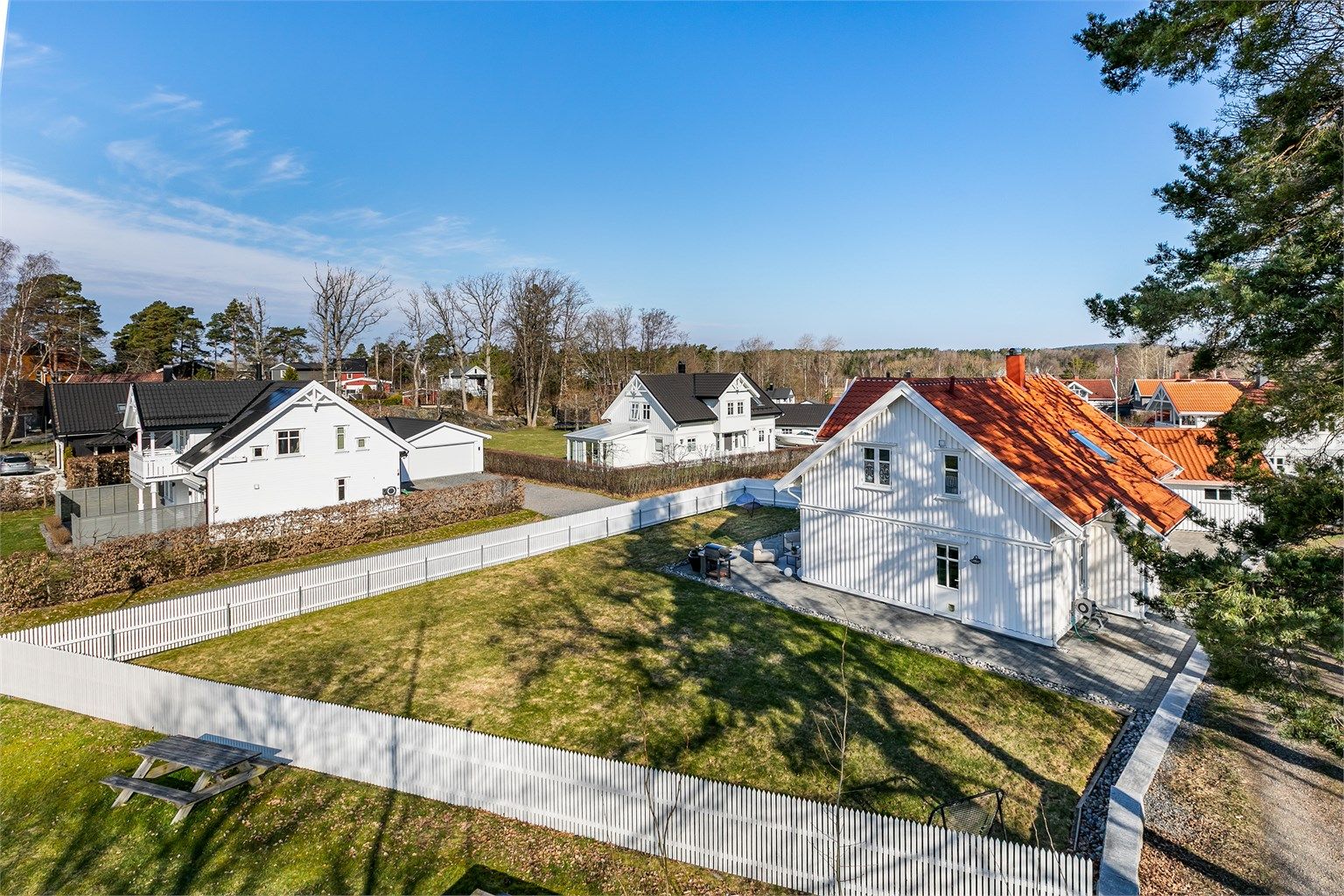 Hvitmalt stakittgjerde rammer pent inn den store, men lettstelte hagen.