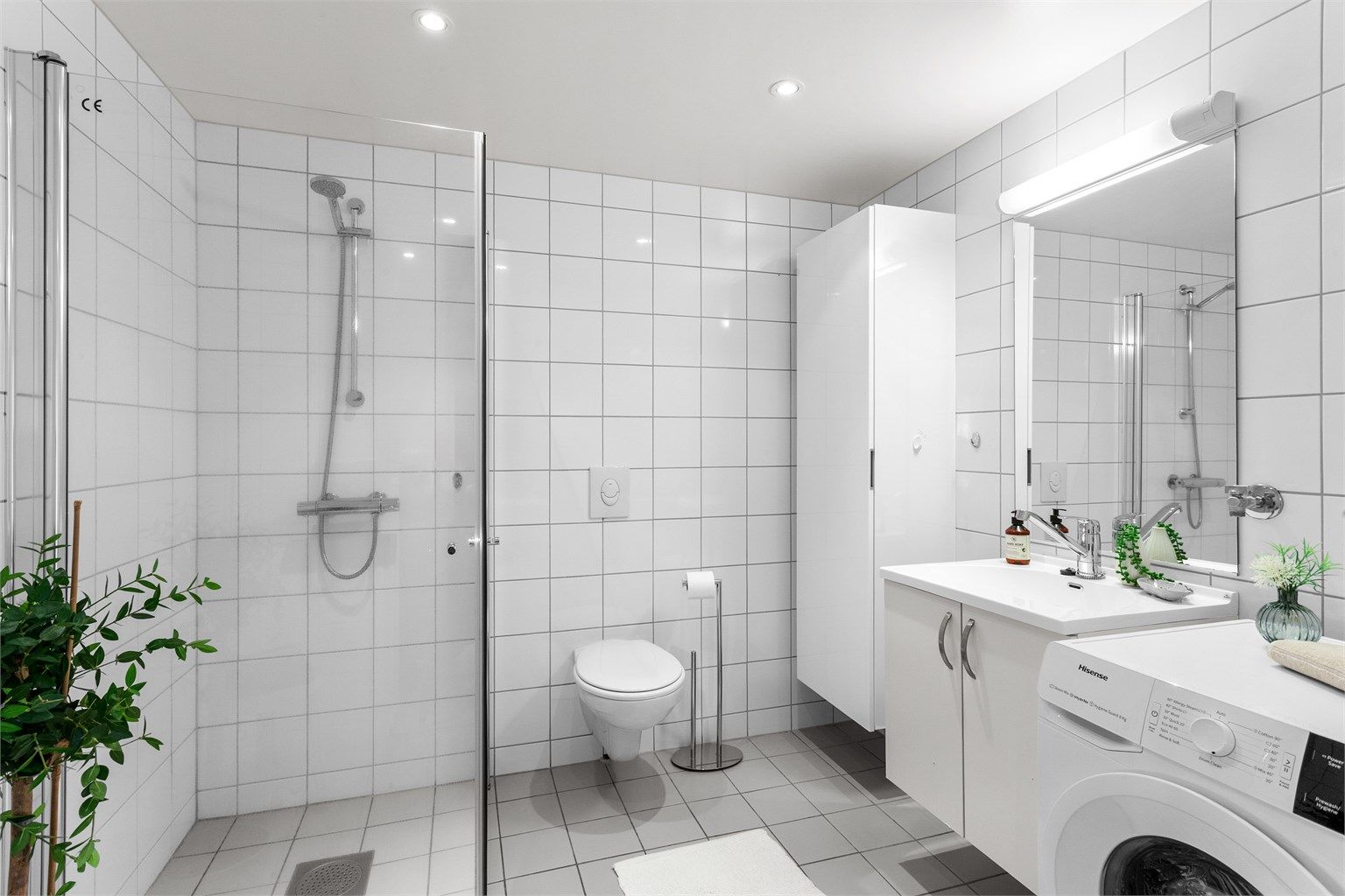 Flislagt bad med gulvvarme. Himling med downlights. Vegghengt servantinnredning med ovenpåliggende servant. Dusjhjørne med dører i glass.