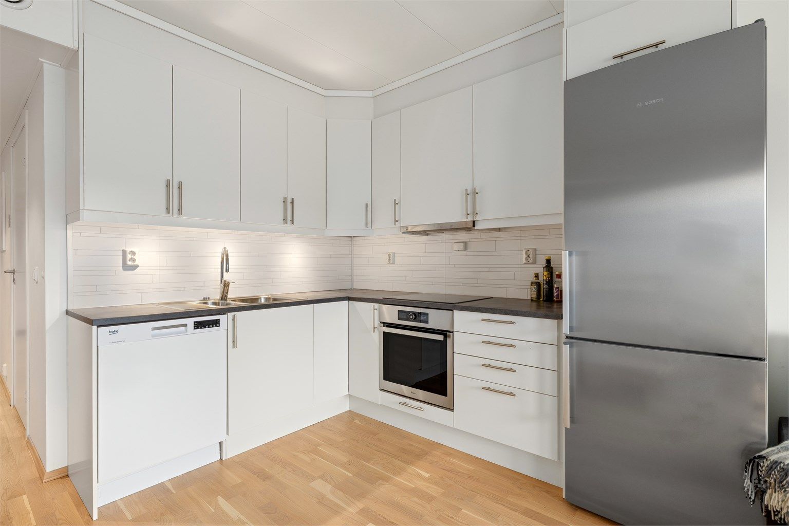 Moderne kjøkken med takhøye skap. Komfyrvakt er montert. Avtrekk over kokeplaten går ut.